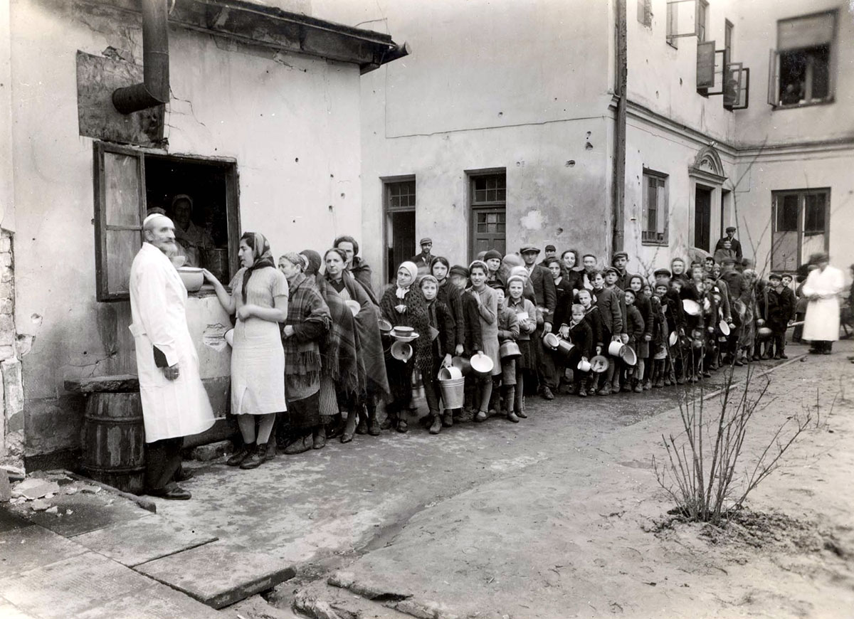 פליטים יהודים ממתינים בתור במטבח ציבורי ברחוב נאלבקי 33 בגטו ורשה. ברחוב זה נמצאו בעיקר פליטים מקאליש-ליפנו