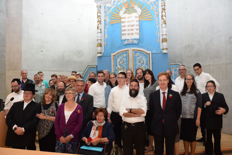 Survivor Tova Silverstein surrounded by her family, as well as Andre Larose and Belgian Ambassador to Israel H.E. Mr. John Cornet D'elzius, in the Yad Vashem Synagogue