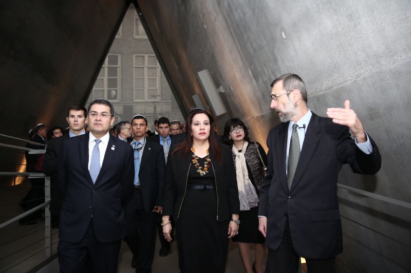 The President of the Republic of Honduras Juan Orlando Alvarado Hernandez (left) at the entrance to the Holocaust History Museum. In the background is &quot;The World that Was,&quot; the first gallery of the Museum, comprising a unique 13-m high video art