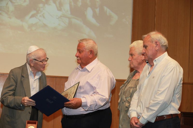 Holocaust survivor Moshe Ha-Elion presents the certificate and medal to the children of the Righteous, Evangelis, Helene and Michalis Voliotis