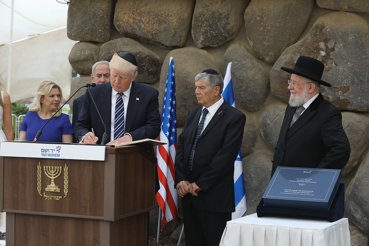 נשיא ארצות הברית דונלד טראמפ חותם בספר האורחים של יד ושם, לצד יו"ר יד ושם אבנר שלו