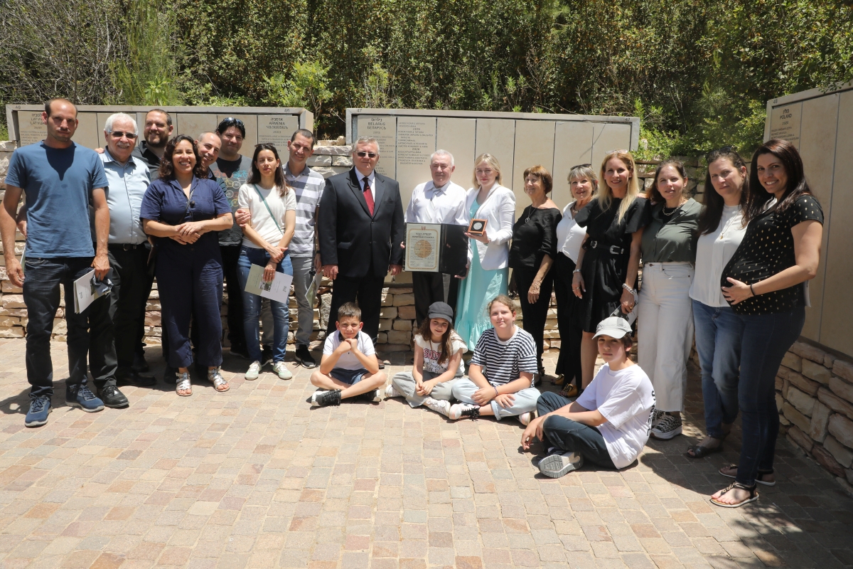 משפחות הניצולים לצד פנטלי לאקוטקו ושגריר בלארוס בישראל לצד שמות המצילים על הקיר בגן חסידי אומות העולם