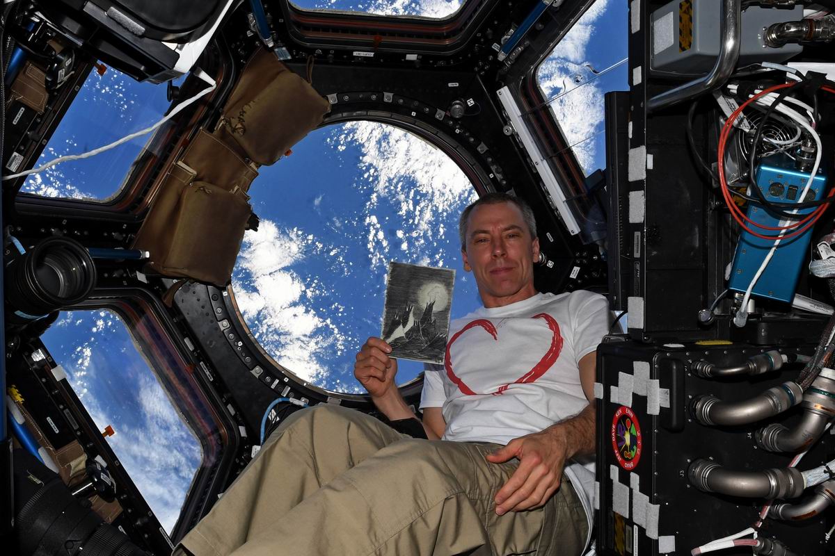 Drew Feustel holding a replica of "Moon Landscape" while orbiting the Earth