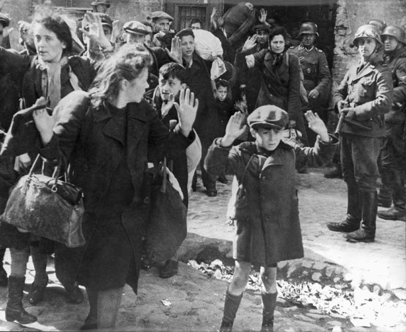 ילד מרים ידיים בעת הוצאת יהודים מהבונקרים בזמן הכנעת המרד בגטו, ורשה, פולין, 1943