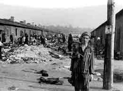 Een voormalig gevangene naast de barakken in het kamp Bergen-Belsen, Duitsland.