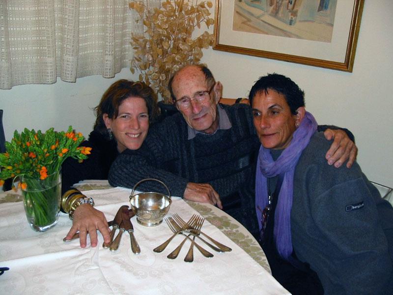 סיומה סלובין (במרכז) עם בנותיו טליה טאיץ (מימין) ואילנה שולמן. על השלחן מונחים כלי הכסף של משפחתו שהושבו אליו בזכות מאגר המרכזי של שמות קרבנות השואה. מאי 2006