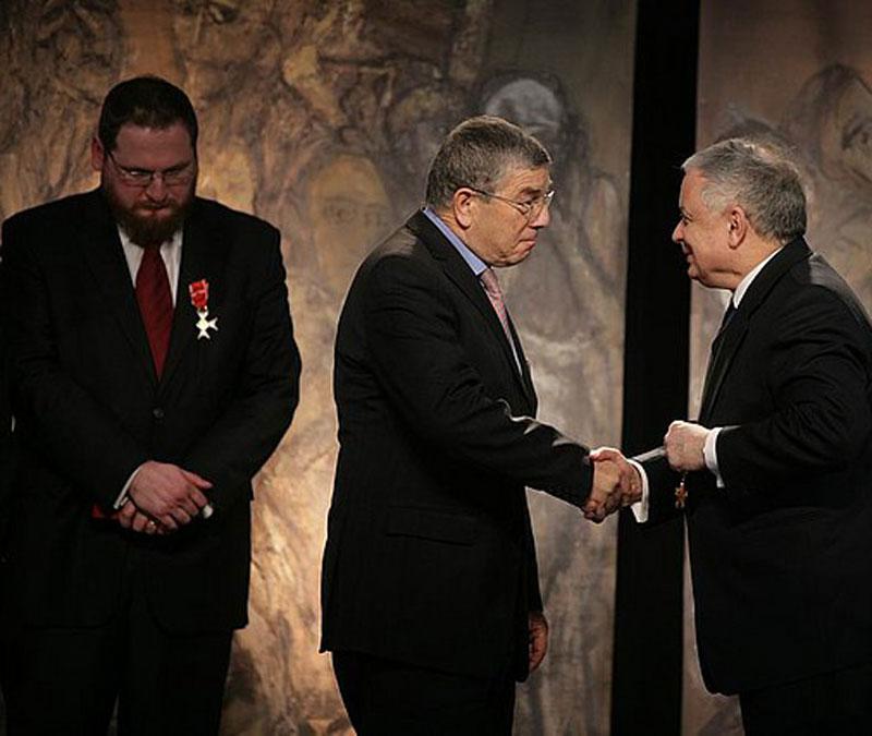 יושב ראש הנהלת יד ושם אבנר שלו (במרכז) לוחץ את ידו של נשיא פולין לך קצ'ינסקי במעמד הענקת עיטור "קצין במסדר הכבוד של רפובליקת פולין". משמאל: מנהל המוזיאון הממלכתי אושווויץ-בירקנאו ד"ר פיוטר צ'יווינסקי.