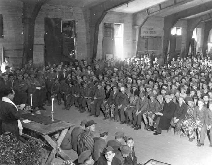 Celebration of Sabbath in Buchenwald after liberation. Lolek is sitting between two American soldiers in the first row on the left