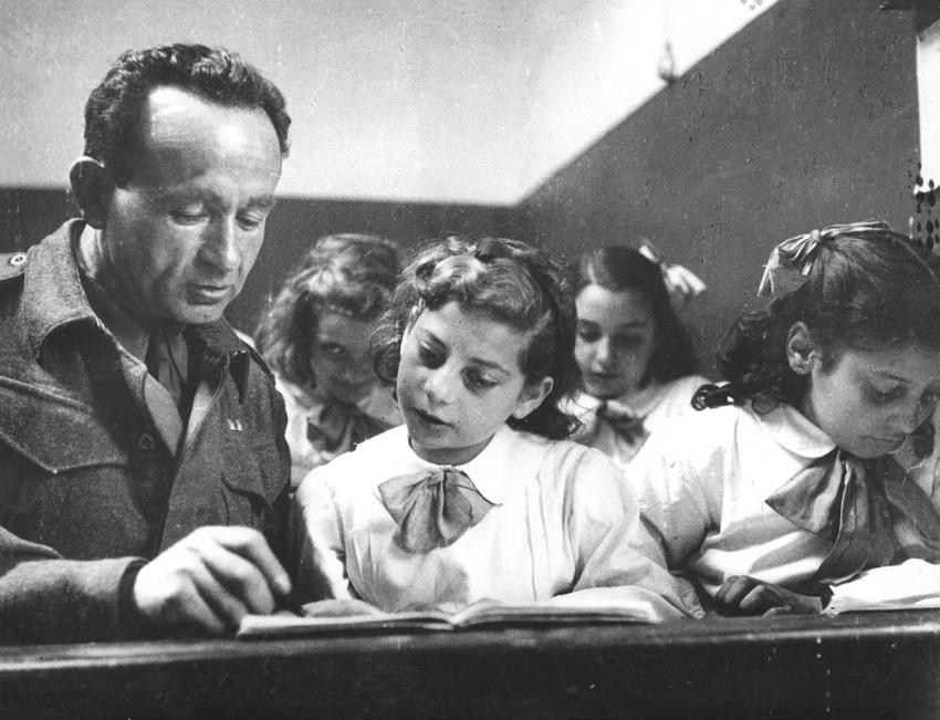 A soldier from Eretz Israel serving in the British Army teaches Jewish children Hebrew in a camp in Italy after the war.
