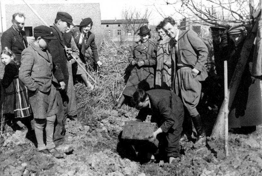 הנריק רוס בעת הוצאת קופסא עם נגטיבים שצילם בגטו לודז', מרס 1945