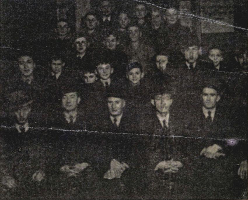 אביה של גניה, קלמן-לייב וולפיילר (יושב באמצע), מנצח על מקהלת גברים בגטו קרקוב. חנוכה, דצמבר 1941.  