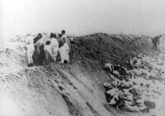 Women and children stand on the edge of a pit before their execution 
