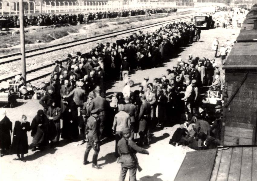 Selección en la plataforma, Birkenau, Polonia, 27.5.1944. Las personas están en camino a la cámara de gas II, cuyo crematorio es discernible en el centro de la fotografía, arriba.