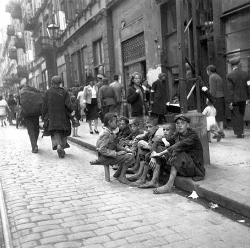 (3) Jóvenes sentados en una acera del gueto de Varsovia
