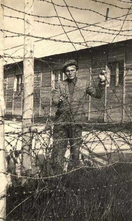 A survivor stands behind barbed wire at the Displaced Persons camp in Bari, Italy, 1947