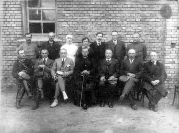 Z. L. Hoffman, a philanthropist born in Mir (sitting 3rd from left) who came on a visit from the US with Jewish representatives, in the courtyard of the town council, Mir, 1926.  Among those sitting: Shaul Roskowski (right), Binyamin Goldin (3d from left)