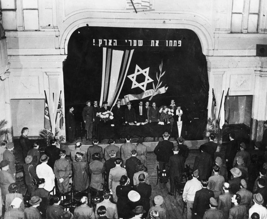 Holocaust refugees’ conference held in Rome in October and November 1945. Representatives of refugees and displaced persons from all over Italy participated. The banner on the stage reads Open the Gates of Eretz Israel!