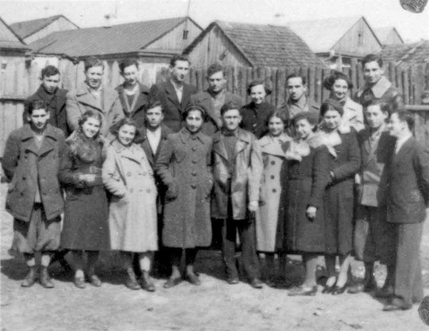 Group of youth from Mir in front of wooden houses in the town