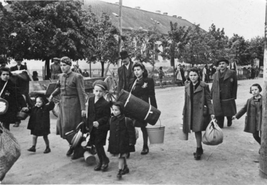 Tova Mendel (con pañuelo en la cabeza) y Salomon Findling (el hombre alto detrás de Tova) y sus hijos Frederika, Helena, Mikulas e Israel, siendo deportados junto a otros judíos de Stropkov, Eslovaquia, 23 de mayo de 1942