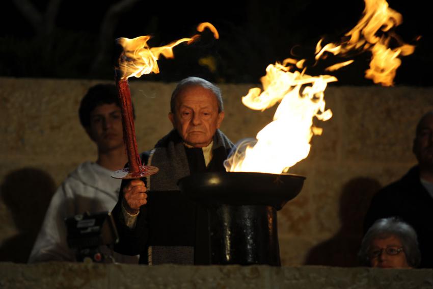Holocaust survivor Andrei Calarasu lights one of the six torches at the ceremony