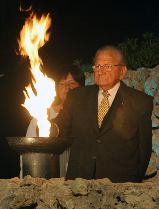 Yaacov (Jacki) Handeli, one of the designated torchlighters, lights a torch during the ceremony