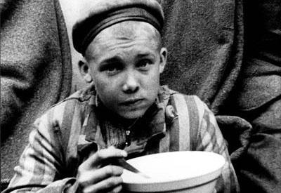 נער במדי אסיר אוכל את ארוחתו הראשונה, בזמן השחרור, מחנה דכאו, גרמניה