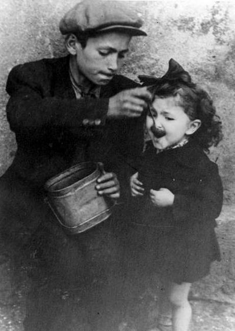Un muchacho alimentando a su hermana en el Ghetto de Lodz