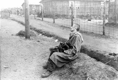 ניצול יושב מחוץ לצריף בברגן-בלזן, גרמניה, אפריל 1945