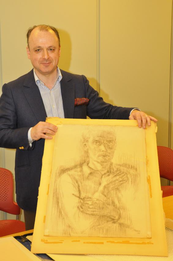  Dr. Matthias Stahl holding a self-portrait painted by his father, Mario Stahl