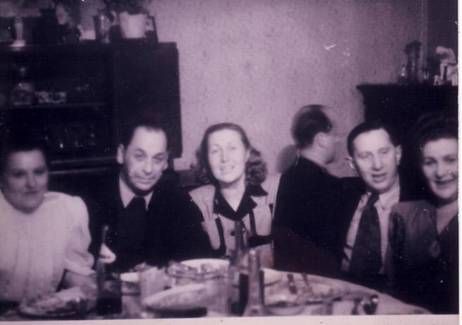 Послевоенная фотография. Застолье в доме семьи Нойм. В центре сидят супруги Нойм. У пианино – Гарри Ицигсон (один из спасенных)