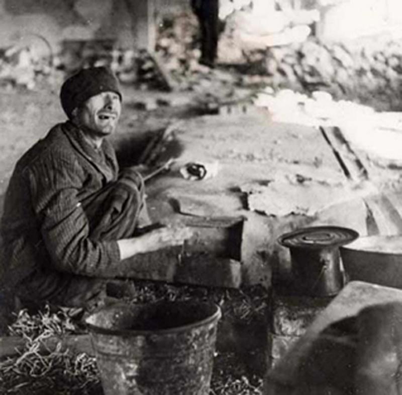 A survivor sits near a pot of potatoes at the Dora-Mittelbau Concentration Camp in Germany