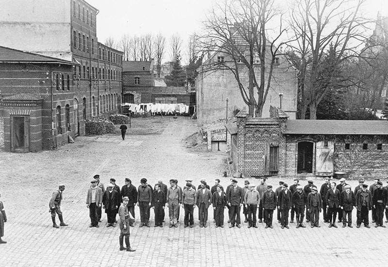אנשי SA שומרים על אסירים העומדים בשורה במחנה, אורניינבורג, גרמניה, 06/04/1933.