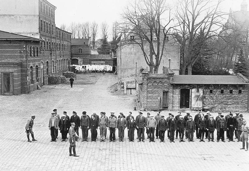אנשי SA שומרים על אסירים העומדים בשורה במחנה הריכוז אורניינבורג, גרמניה, 06/04/1933