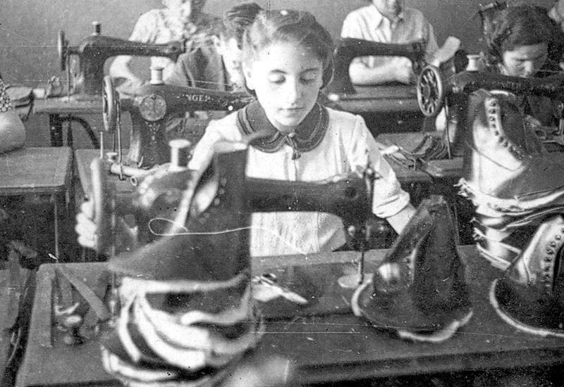 אולם מכונות תפירה המופעלות רגלית בבית מלאכה לייצור נעליים בגטו ששימש לייצור עבור הורמכט, לודז', פולין