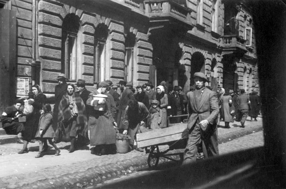Crowded street scene in the Warsaw ghetto, captured from inside a moving vehicle