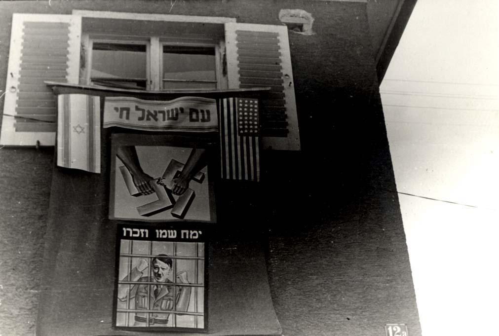 Posters hanging from windows during a Purim parade, Landsberg, Germany, 1946