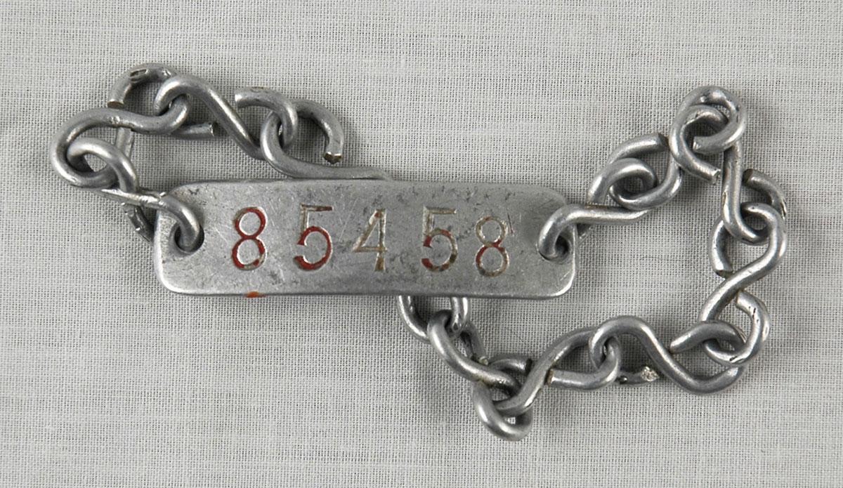 Brazalete de metal con el número de prisionero 85458 que Arieh Mühlrad fue obligado a portar en el campo de concentración de Plaszow