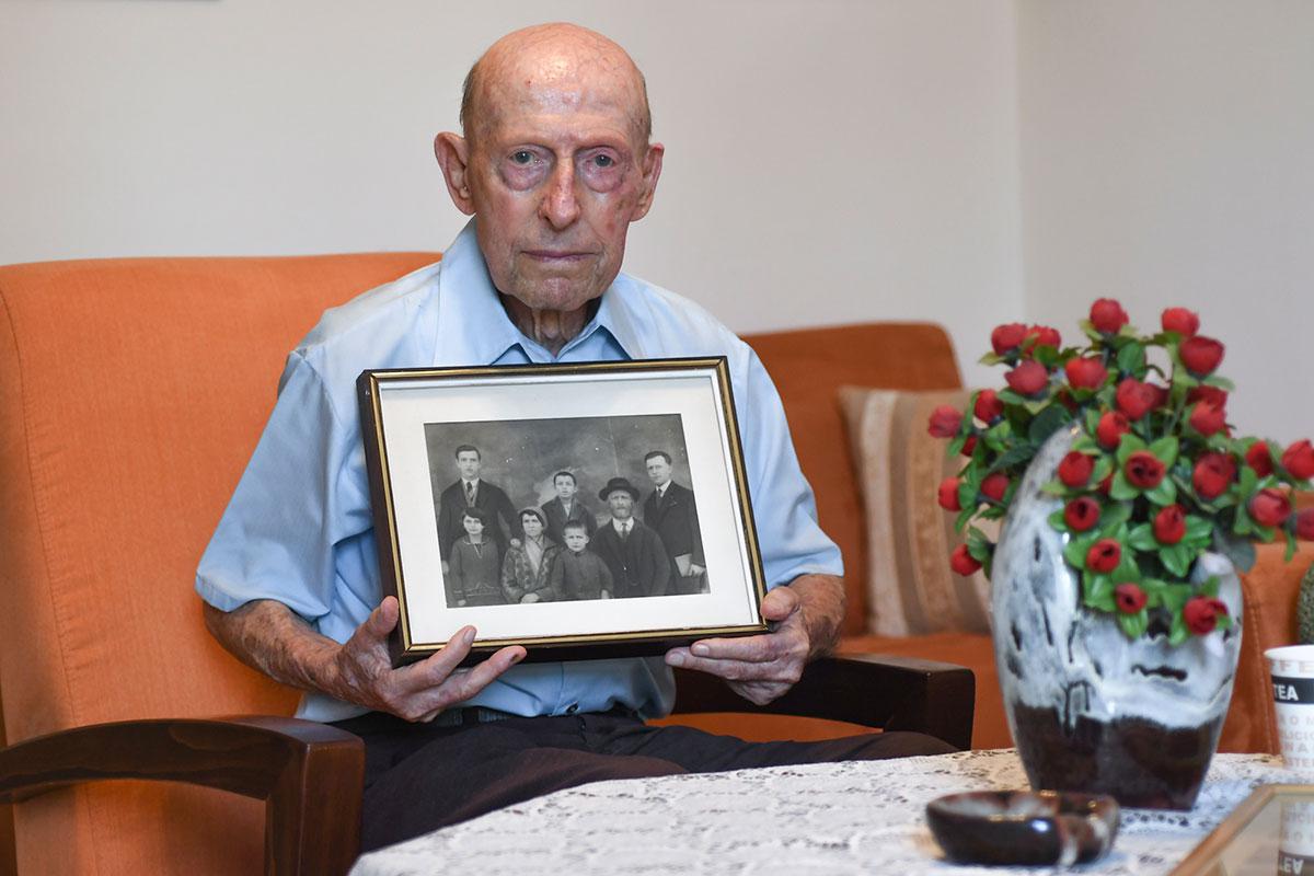 ניצול השואה יוסף קורנבליט אוחז בתמונה של משפחתו. רוב בני המשפחה נרצחו בשואה.