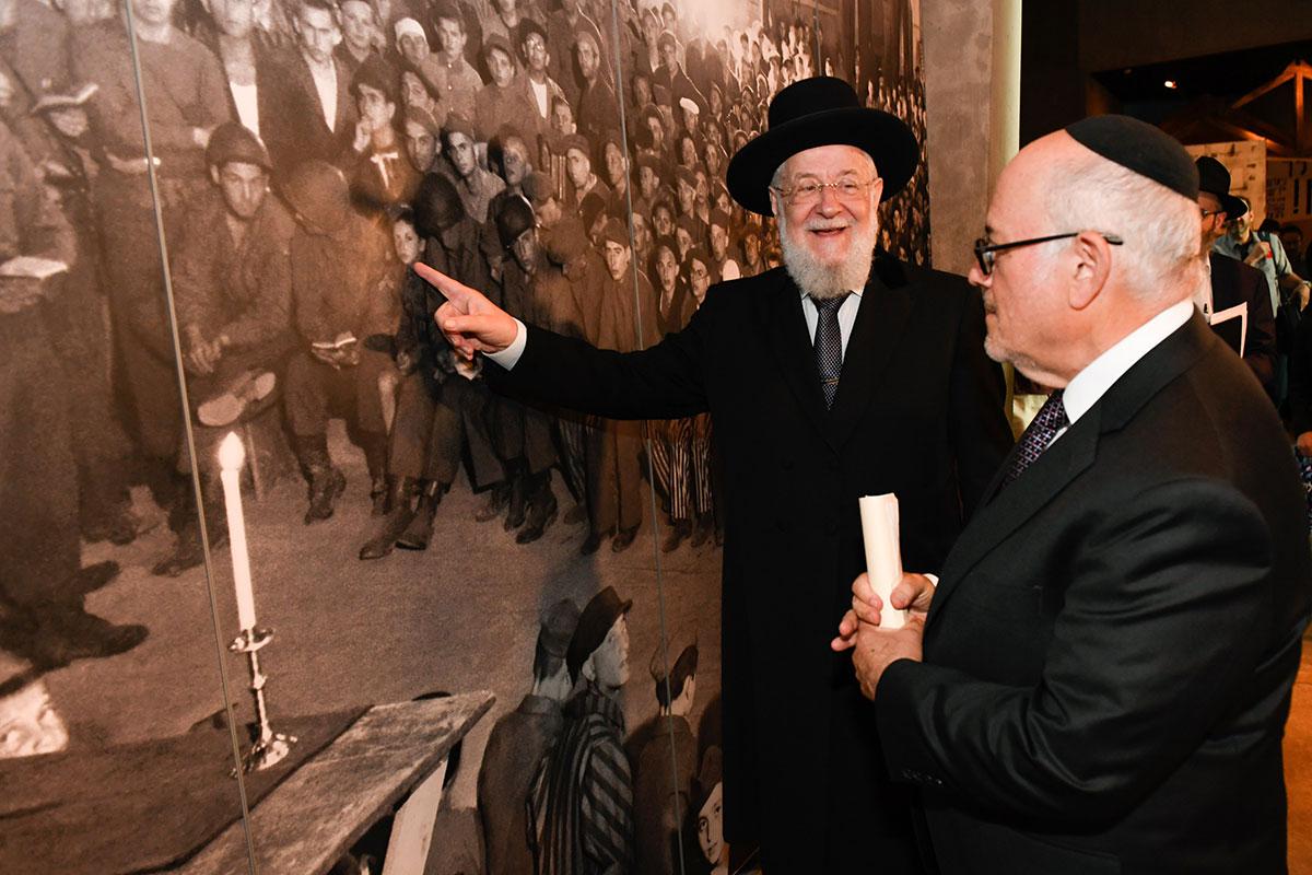 Yad Vashem Council Chairman Rabbi Israel Meir Lau (left) points to himself as a young boy in a photograph of a liberation ceremony at Buchenwald, displayed in Yad Vashem's Holocaust History Museum