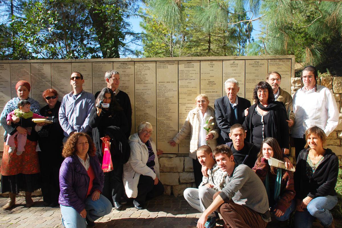 The family of survivor Hedva Gil (standing by wall holding a flower) who was saved by Righteous Among the Nations Adolf Otto, at a ceremony with his Otto's daughter Anna Suchecka (kneeling next to the wall) at Yad Vashem, November 28, 2011