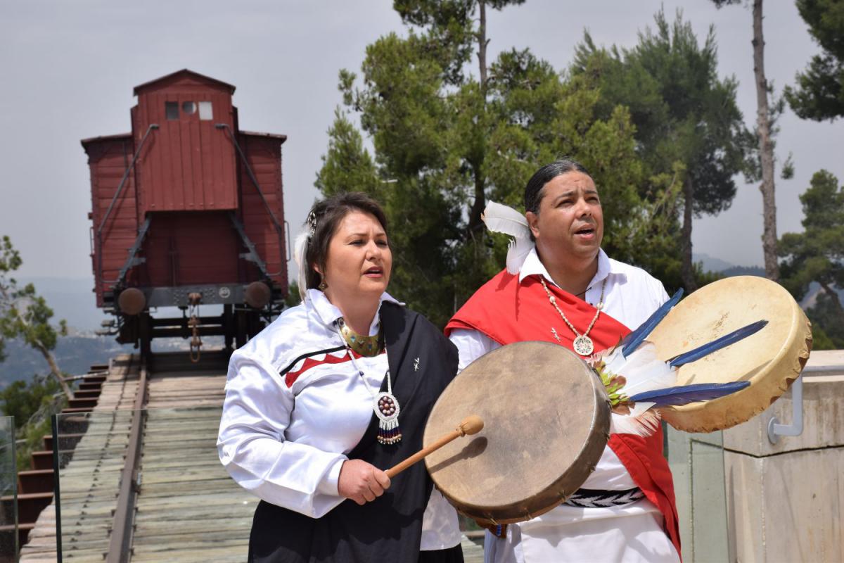 Chief Joseph &amp; Dr. Laralyn River Wind of the Northern Arawak Tribal Nation performing a song written about those transported and murdered during the Holocaust in front of the Cattle Car - Memorial to the Deportees monument at Yad Vashem on 28th May 2018