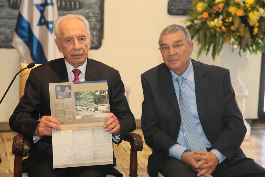 Israeli President Shimon Peres holding the memento  presented to him by Yad Vashem Chairman Avner Shalev