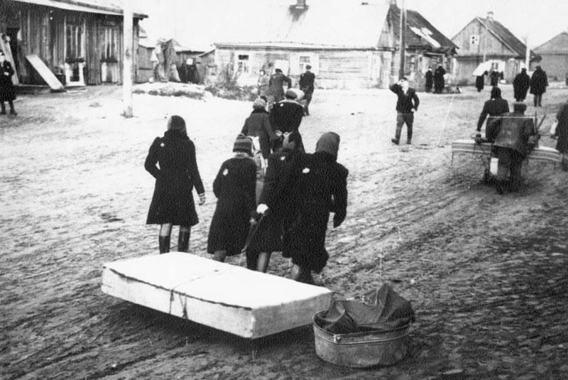 נשים וילדים גוררים את חפציהם במעבר אל הגטו