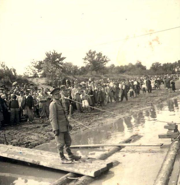 יהודים מגורשים ממתינים לרפסודה שתעביר אותם לטרנסניסטריה, מוגילב פודולסקי, אוקראינה, 10 ביוני, 1942. ארכיון יד ושם.