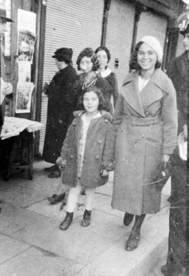 פרידה (בת חמש וחצי) ואחותה אנה מטיילות ברחובות צ'רנוביץ, חורף 1939. בדוכן מאחור נראה עיתון ובו פניו של היטלר