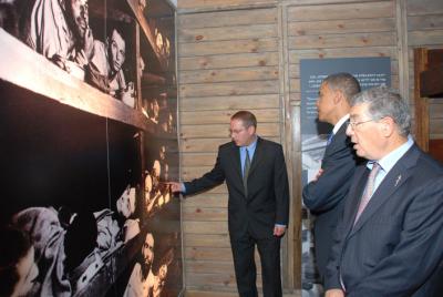הסנטור ברק אובמה (במרכז), מתבונן בתמונה משחרור מחנה בוכנוואלד במוזיאון לתולדות השואה ביד ושם. המדריך גיא שמר (משמאל), מצביע על חתן פרס נובל, אלי ויזל שמצולם בתמונה