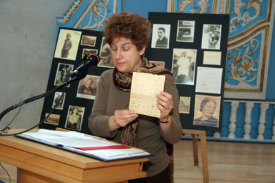 ד&quot;ר דיאנה פלשר נושאת דברים בטקס ומציגה את המכתב האחרון שכתבו בני משפחת פלשר ליואכים לפני שנרצחו