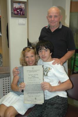 Naomi and Morris Shlomovitz with their grandson Matthew Glaser holding a memorial certificate for Naomi's grandfather Zisha Katz