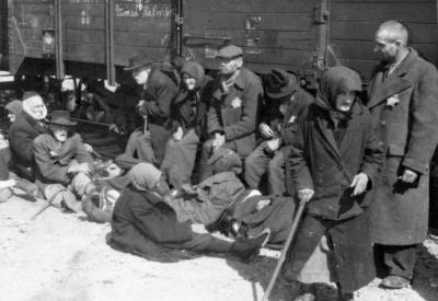 Zum Tod selektierte ältere Männer und Frauen warten auf der Rampe, bevor sie in die Gaskammer gebracht werden. In Birkenau wurden ältere Menschen fast sofort ins Gas geschickt, da man sie als „arbeitsunfähig“ einstufte.