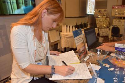 Debbie Berman of the Names Recovery Project at Yad Vashem helps to fill out nine Pages of Testimony submitted by a conference attendee